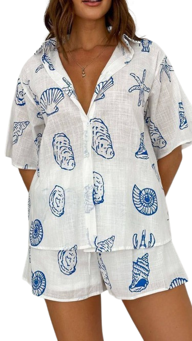 Woman wearing white pajama set with blue seashell print pattern.